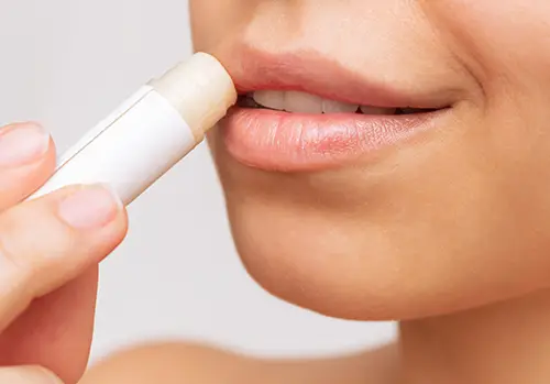 a young woman applying lipstick on her lips