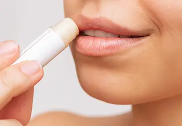a young woman applying lipstick on her lips