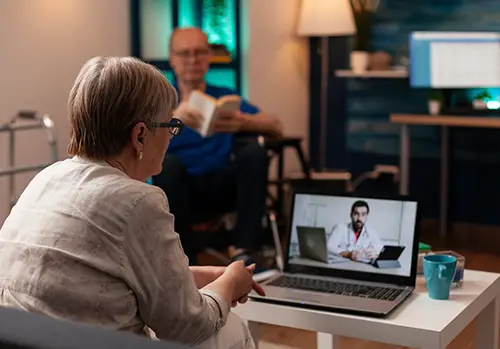 older patient using telemedicine on video call conference while sitting on couch at home