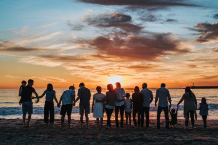A large group of people watches the sun set over the ocean. Thanks to their state's Medicaid expansion, they all have access to affordable healthcare.