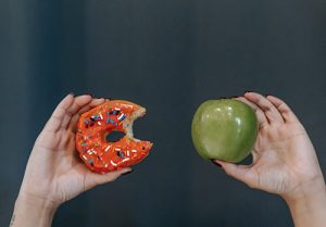 A person compares a donut versus an apple as a fullness factor concept