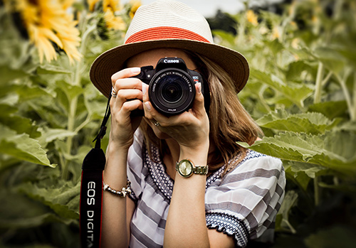 A woman properly holds a photography camera.