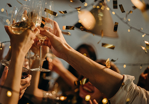 Champagne glasses touch at a New Year's Eve celebration.