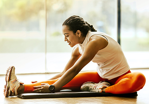 Woman stretches on mat inside of gym to work on her health.