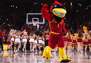A cardinal college mascot celebrates on the basketball court.