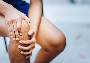 A person clutches their knee joint in pain.