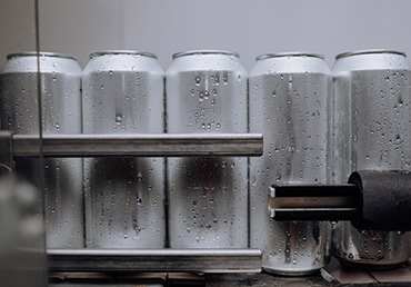 Unlabeled energy drink cans are processed in a factory.