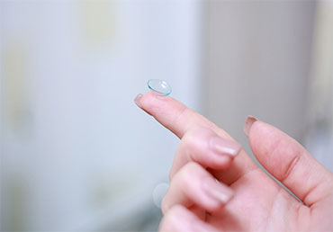 woman holding a contact lens on her finger