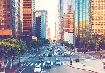 Cars drive through a busy intersection in downtown Los Angeles.