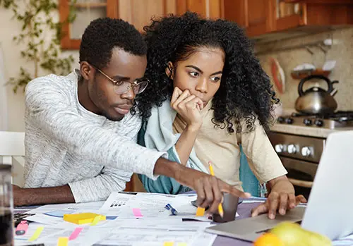 A couple studies different kinds of medical insurance as they go over their bills. 