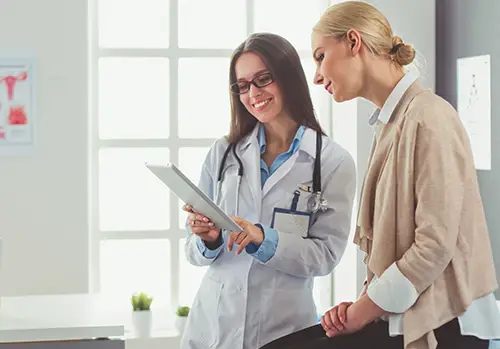 female-patient-sitting-on-table-next-to-doctor