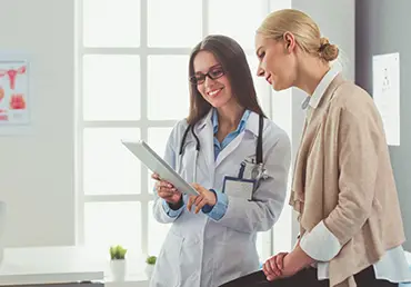 female-patient-sitting-on-table-next-to-doctor