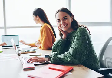 Female college student smiling with computer and books for health insurance.