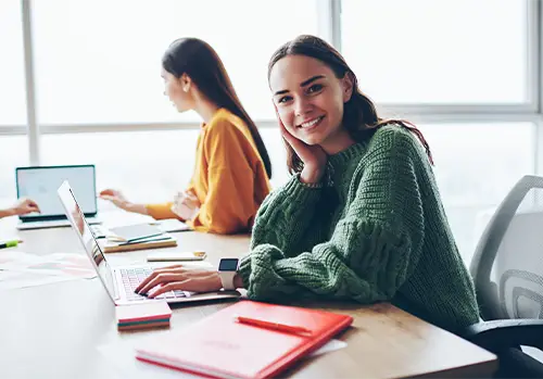 Female college student smiling with computer and books for health insurance.