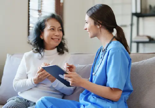 woman and nurse sitting and talking smiling large image