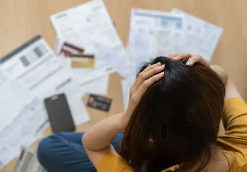 woman stressed sitting above medical bills and credit cards large image
