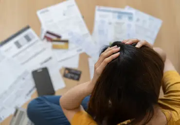 woman stressed sitting above medical bills and credit cards thumbnail image