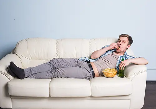 Man with beer and chips watching TV at home