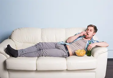 Man with beer and chips watching TV at home